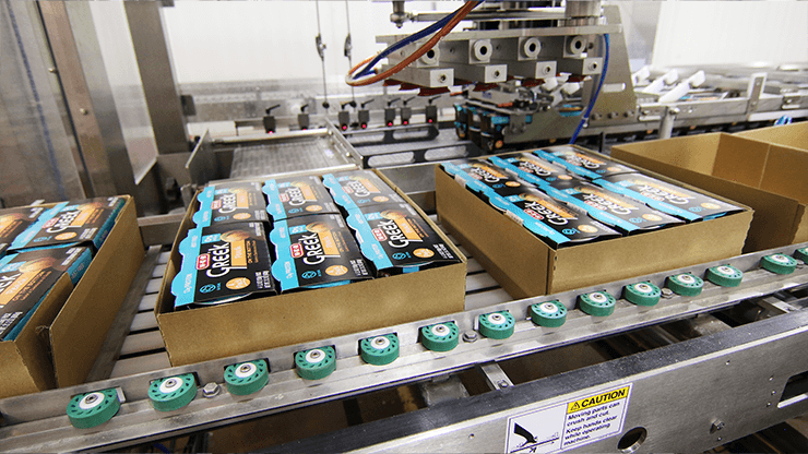 Cartons of yogurt tubs packed into a case running down a Delkor line