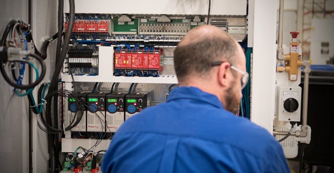 Technical support and service technician examining electrical control panel for delkor machine