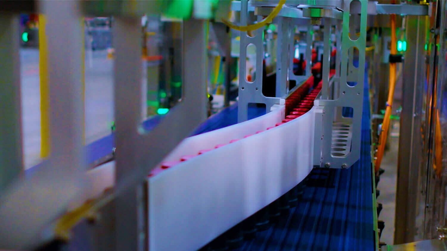 A close-up view of Delkor's patented servo laner running rows of bottled beverages with red caps