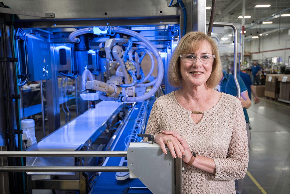 Delkor's VP of Human Resources Patty Andersen poses in front of a Delkor machine