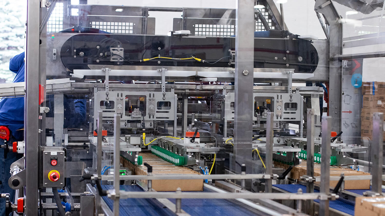 An image of the dual infeed on Delkor's L Series Lidder with cheese product in corrugate boxes on a conveyor belt