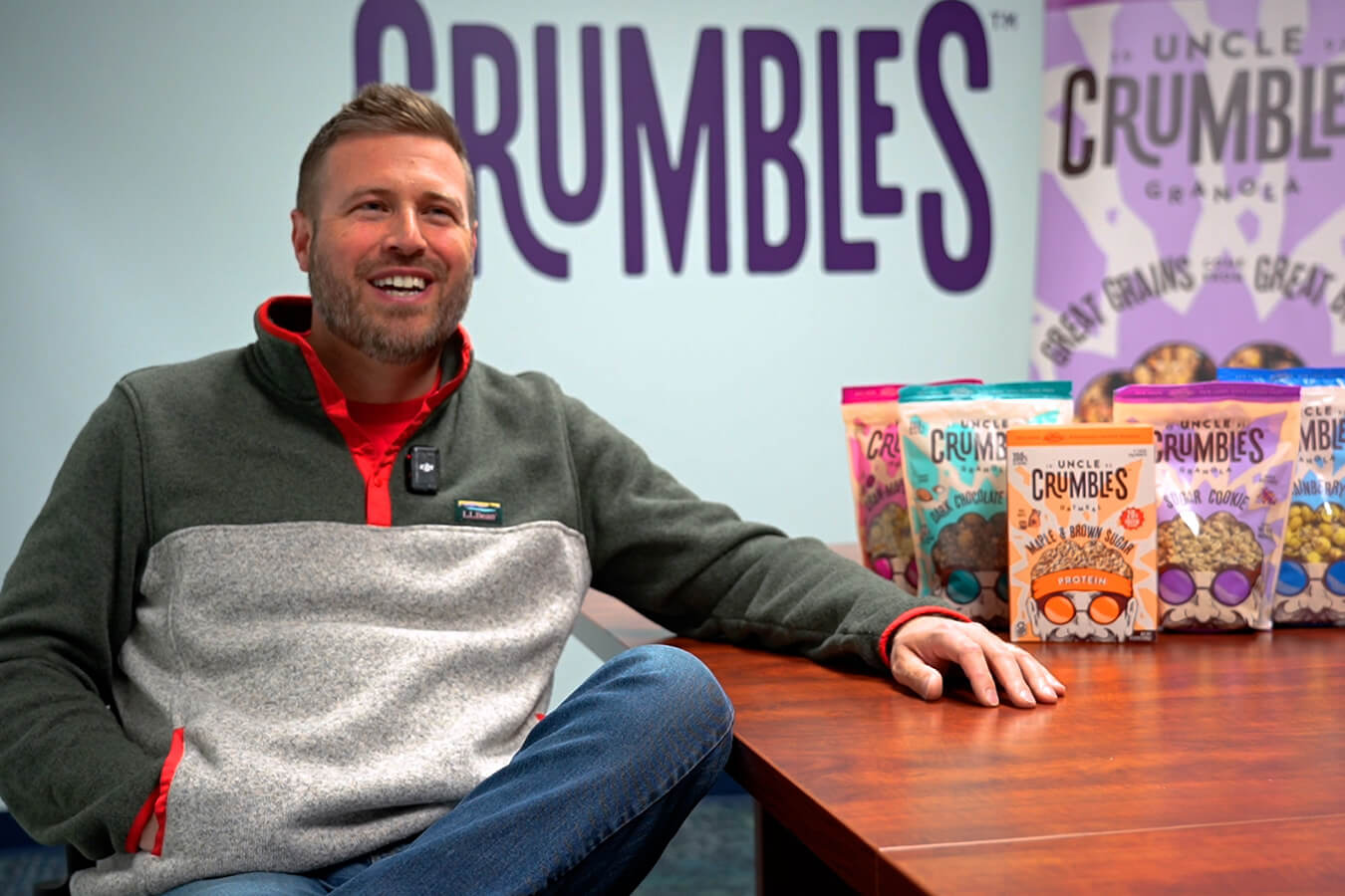 Uncle Crumbles President & CEO James Shutts sits near a table with granola products on it